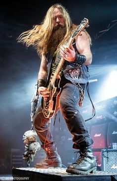 a man with long hair playing guitar on stage