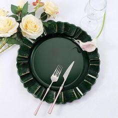 there is a green plate with silverware on it and some flowers in the background