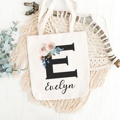 a tote bag with the letter e on it next to some flowers and leaves