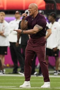 a man with a microphone standing on top of a field in front of other people