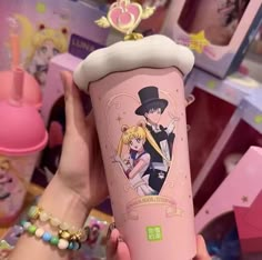 a person holding up a pink cup with anime characters on it