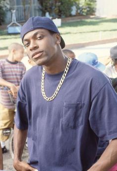 a man in a blue shirt and hat standing next to other men wearing black caps