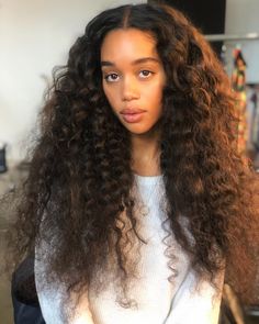 a woman with long curly hair is sitting in a chair and looking at the camera