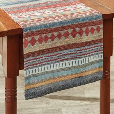 a wooden table topped with a multicolored rug on top of it's legs