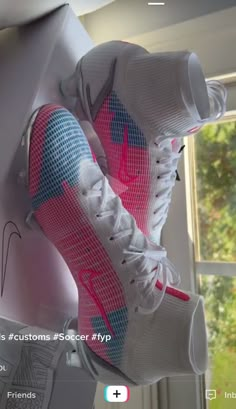 a pair of white and pink sneakers hanging from the side of a window sill