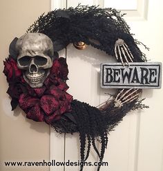 a halloween wreath with a skeleton holding a sign that says beware and roses on it