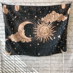 a tapestry hanging on a brick wall with the sun and moon