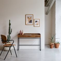 a desk and chair in a room with two framed pictures on the wall above it