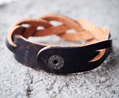 a close up of a leather bracelet with a metal button on it's end