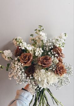 a person holding a bouquet of white and brown flowers