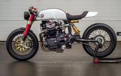 a white and black motorcycle parked in front of a garage