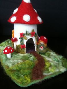 a close up of a small house made out of wool with mushrooms on the roof