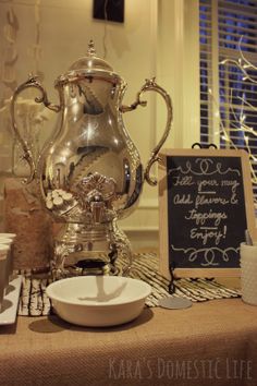 a silver tea pot sitting on top of a table next to a plate and cup