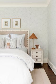 a white bed sitting in a bedroom next to a nightstand with two teddy bears on it