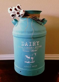 a blue milk can with cotton flowers in it