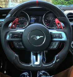 the interior of a sports car with steering wheel controls and gauges on display in front of a brick building