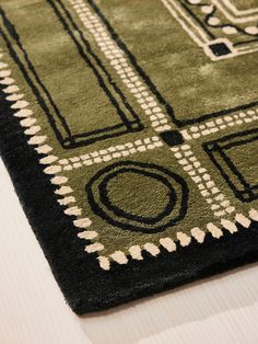 a green and black area rug on top of a white table with a wooden floor