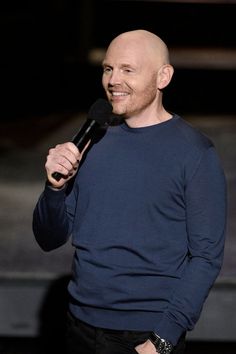 bald man in blue shirt holding a microphone