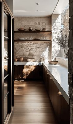 a long narrow kitchen with wooden cabinets and white counter tops, along with open shelves on the wall