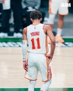 a basketball player standing on the court with his hands in his pockets and looking down