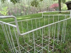 a white metal basket sitting on top of a lush green field