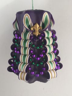 an ornament hanging from a green and white ribbon with purple beads on it