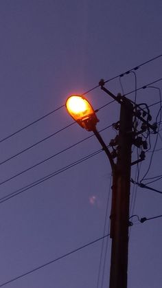 a street light sitting on the side of a pole under power lines at night time