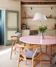 a pink table and chairs in a room with wood beams on the ceiling, light fixture hanging from the ceiling