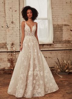 a woman standing in front of a window wearing a wedding dress with flowers on it