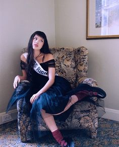 a woman sitting on top of a chair in a room