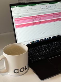 a coffee mug sitting next to a laptop computer