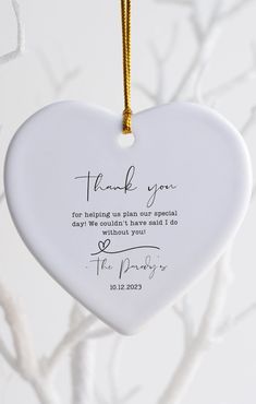 a white heart ornament hanging from a tree with the words thank you written on it