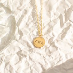 "Not too big and not too small, our 13mm circle necklace, fits just right. A perfect everyday necklace that will layer beautifully with your other chain and pendant necklaces. Engrave a heartfelt word, a special year, or a short name of a loved one. Free Engraving for a limited time! NECKLACE DETAILS ⚬ 14k gold-filled disc and chain. ⚬ Disc measures 13mm (0.51\") ⚬ Chain in your choice of 16\", 18\", or 20\" length ⚬ Spring ring clasp closure. ⚬ Personalized engraving of 1-4 characters (includin Round Charm Necklace With Adjustable Chain For Her, Everyday Tarnish Resistant Charm Necklace With Round Pendant, Classic Round Initial Necklace For Gift, 14k Gold Charm Necklace With Round Pendant For Her, 14k Gold Round Charm Necklace, Circle Charm Necklace In Yellow Gold Sterling Silver, Minimalist Engraved Circle Necklaces, Everyday 14k Gold Round Charm Necklaces, Classic Round Charm Necklaces For Gifts