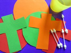 paper cut out to look like crosses on a purple table with orange and green shapes