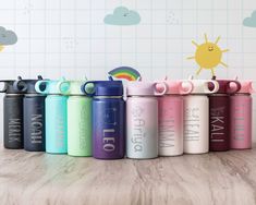 thermos are lined up in front of a wall with sun and clouds on it