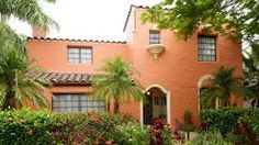 a pink house with palm trees and flowers in the front yard