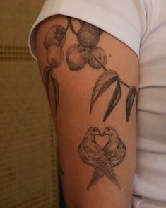 a woman's arm with flowers and two birds on the back of her arm