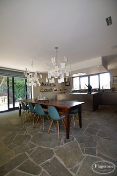 a dining room table with blue chairs and a chandelier hanging from the ceiling