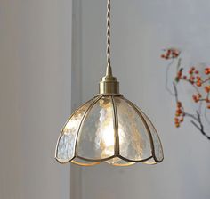 a light fixture hanging from a ceiling in a room with flowers on the wall behind it