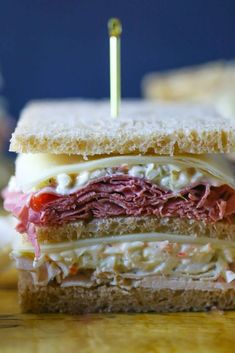 a close up of a sandwich on a wooden table with toothpicks in it