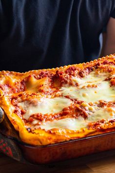 a person holding up a pizza with cheese and sauce