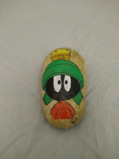 a painted rock with a cartoon character on it's face and hat, sitting on a white sheet