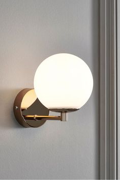 a wall light that is on the side of a wall with a white glass ball