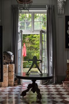 a room with a checkered floor and an open glass door to the garden outside