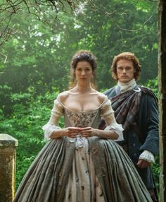 a man and woman in period dress standing next to each other on a wooden platform