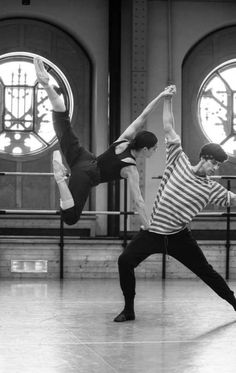 two young men doing tricks on the dance floor in front of large stained glass windows