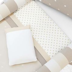 a white pillow sitting on top of a bed next to sheets and pillows with polka dots