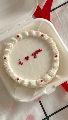 a white cake sitting on top of a table next to a container with writing on it