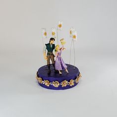 a figurine is standing on top of a purple cake with stars and sparklers