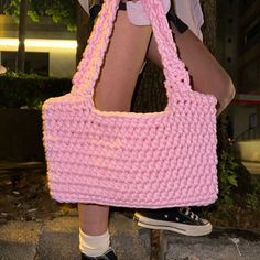 a woman carrying a pink crocheted handbag